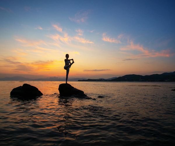 Silhouette of a person in a meditation pose at sunrise.